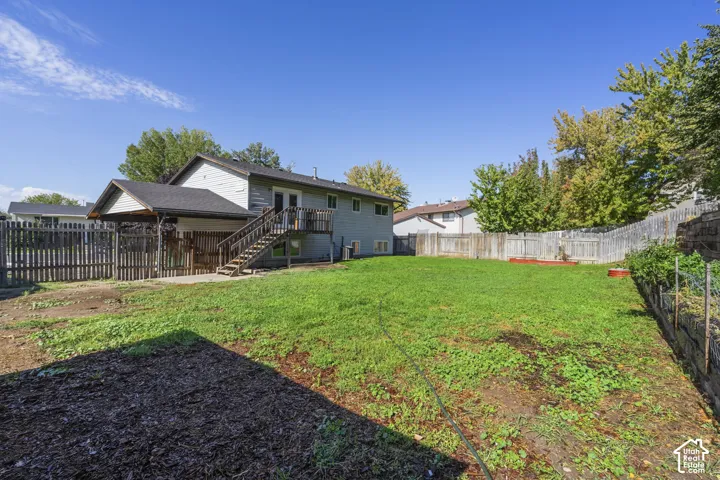 Expansive backyard featuring a manicured lawn, wood fencing, and a built-in garden bed