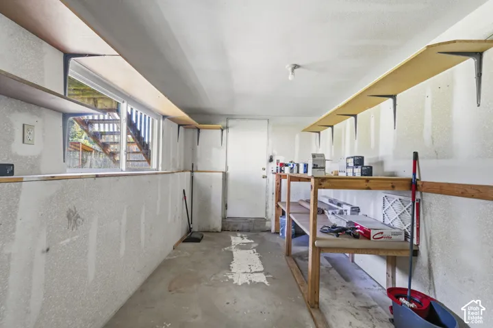 Concrete flooring with exposed walls, featuring a window and overhead shelving