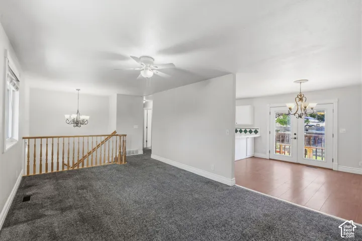 Carpeted living area with a ceiling fan and a staircase featuring a wood-finish railing