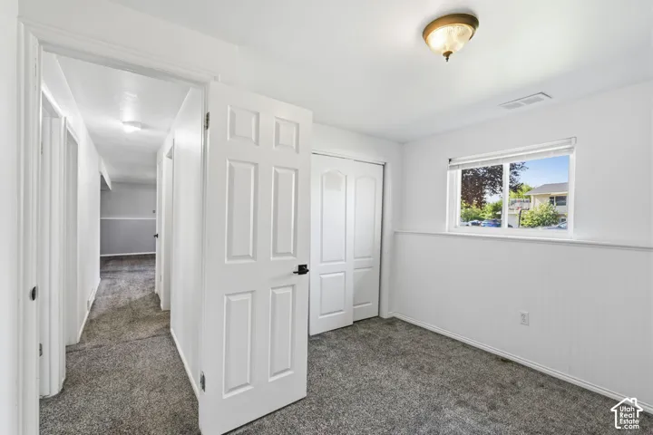 Carpeted room featuring a window, built-in closet with bi-fold doors, and a ceiling-mounted light fixture