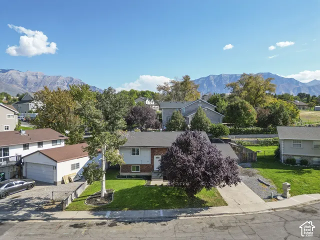 Mountain backdrop, residential property, paved driveway, detached garage structure, mature trees