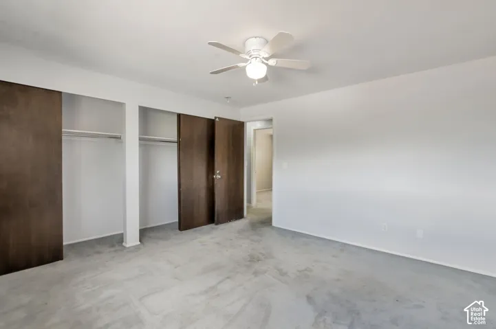 Ceiling fan with integrated lighting, two built-in closets with wood-finish sliding doors, and light-colored carpeting