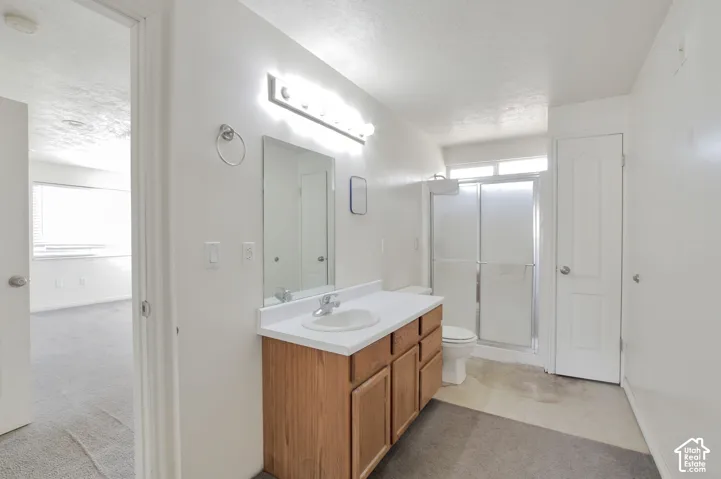 Bathroom featuring a wood-finish vanity with a single basin sink and a shower with sliding glass doors