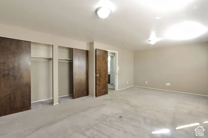 Expansive room with neutral carpeting, recessed wall niche, and built-in closet storage