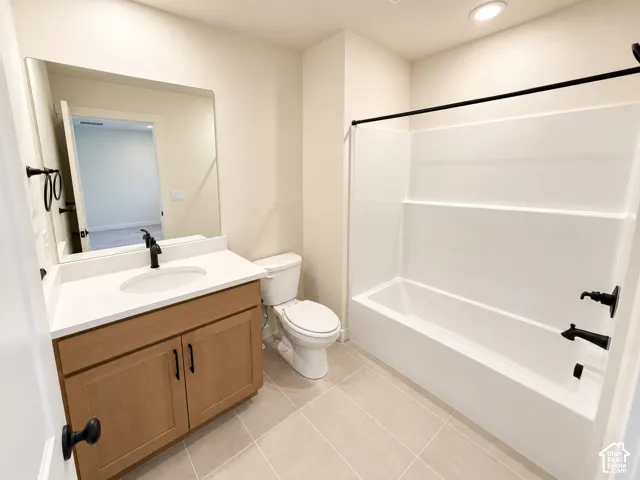 Bathroom featuring a wood-finish vanity with a white countertop, an oval undermount sink, and a white bathtub with a shower