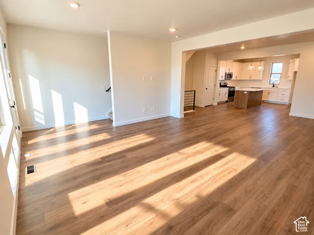 Spacious living area featuring wood-finish flooring, recessed lighting, and an open concept to the kitchen