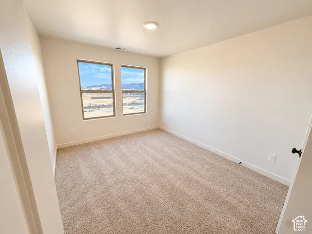 Bright corner bedroom with dual windows framing expansive natural light, neutral wall finishes, and soft carpet flooring throughout