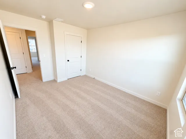 Neutral tone wall paint, light tan carpeting, white trim, and a flush-mount ceiling light