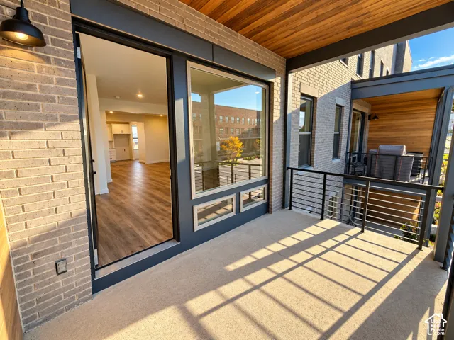 Spacious balcony featuring brick exterior, wood-finish ceiling, and metal railings