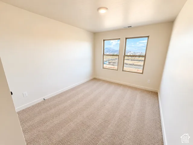 Neutral carpet, two windows with mountain scenery, recessed ceiling light, and light-toned walls