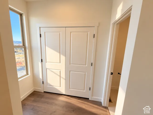 Wood-finish flooring, white paneled bifold doors, and a tall window