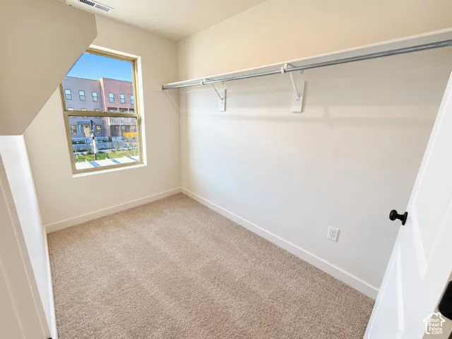 Built-in closet shelving, neutral carpet flooring, white trim, recessed lighting, and a window providing natural light