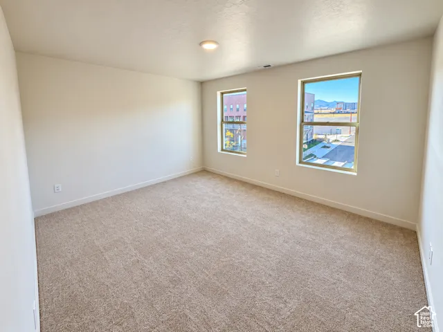 Neutral-toned carpet flooring, crisp white wall paint, two large windows, recessed ceiling light fixture, and white trim