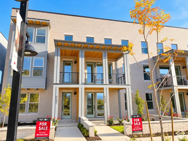 Brick and siding exterior with multiple balconies featuring black railings and wood-finish ceilings