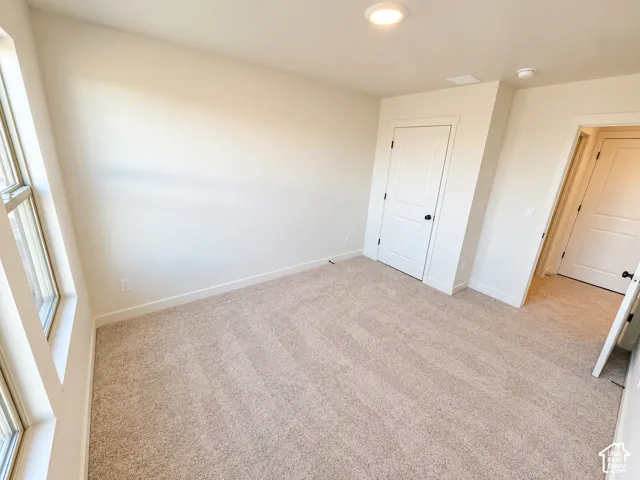 Recessed ceiling lighting, light neutral-toned carpeting, white trim, white walls, and white paneled doors