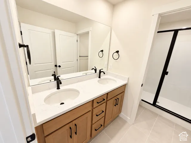 Double vanity with undermount sinks, quartz countertop, wood-finish cabinetry, and matte black fixtures