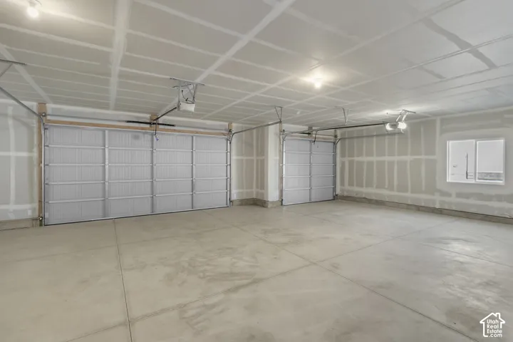 Spacious three-car garage featuring a concrete floor, two overhead garage doors, and an additional window
