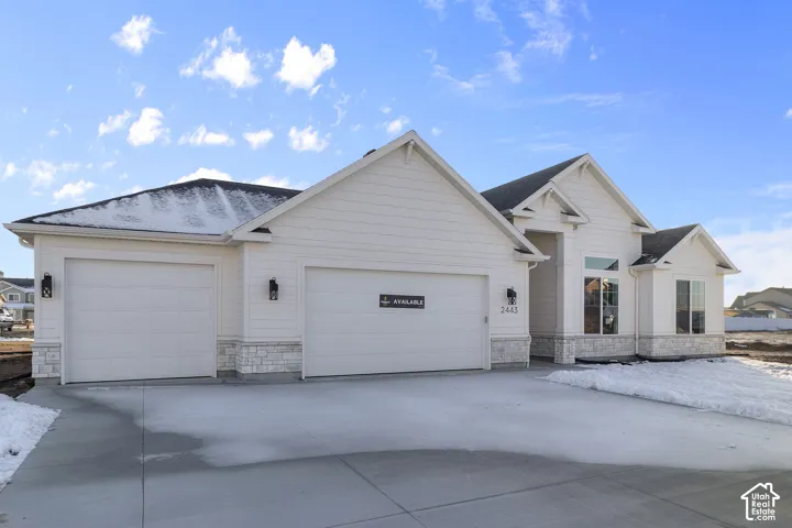 Contemporary exterior featuring white siding, a prominent two-car garage, and stone accents