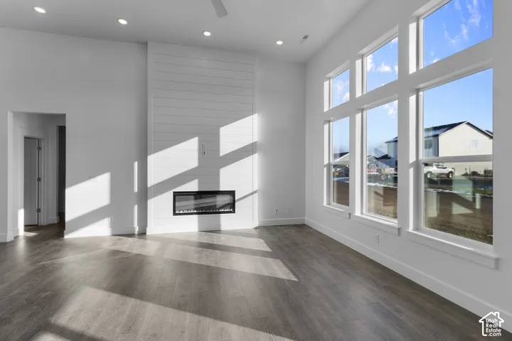 Expansive windows, wood-finish flooring, recessed lighting, electric fireplace, and shiplap-style accent wall