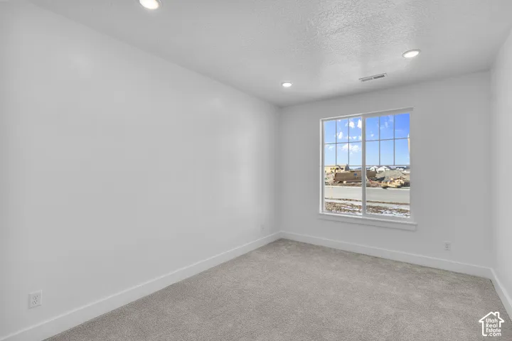 Recessed ceiling lighting, white interior walls, carpeted flooring, and a multi-pane window