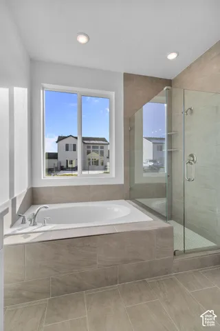 Built-in soaking tub with deck-mounted faucet, tile surround, and frameless glass shower enclosure