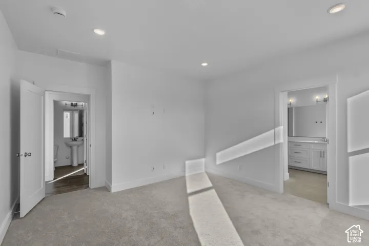 Recessed lighting throughout, light-toned carpeting, and white painted walls