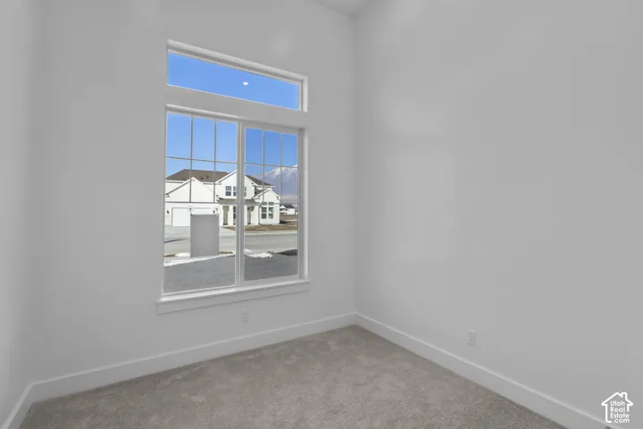 Wall-to-wall carpeting, white painted walls, and a large multi-pane window with transom