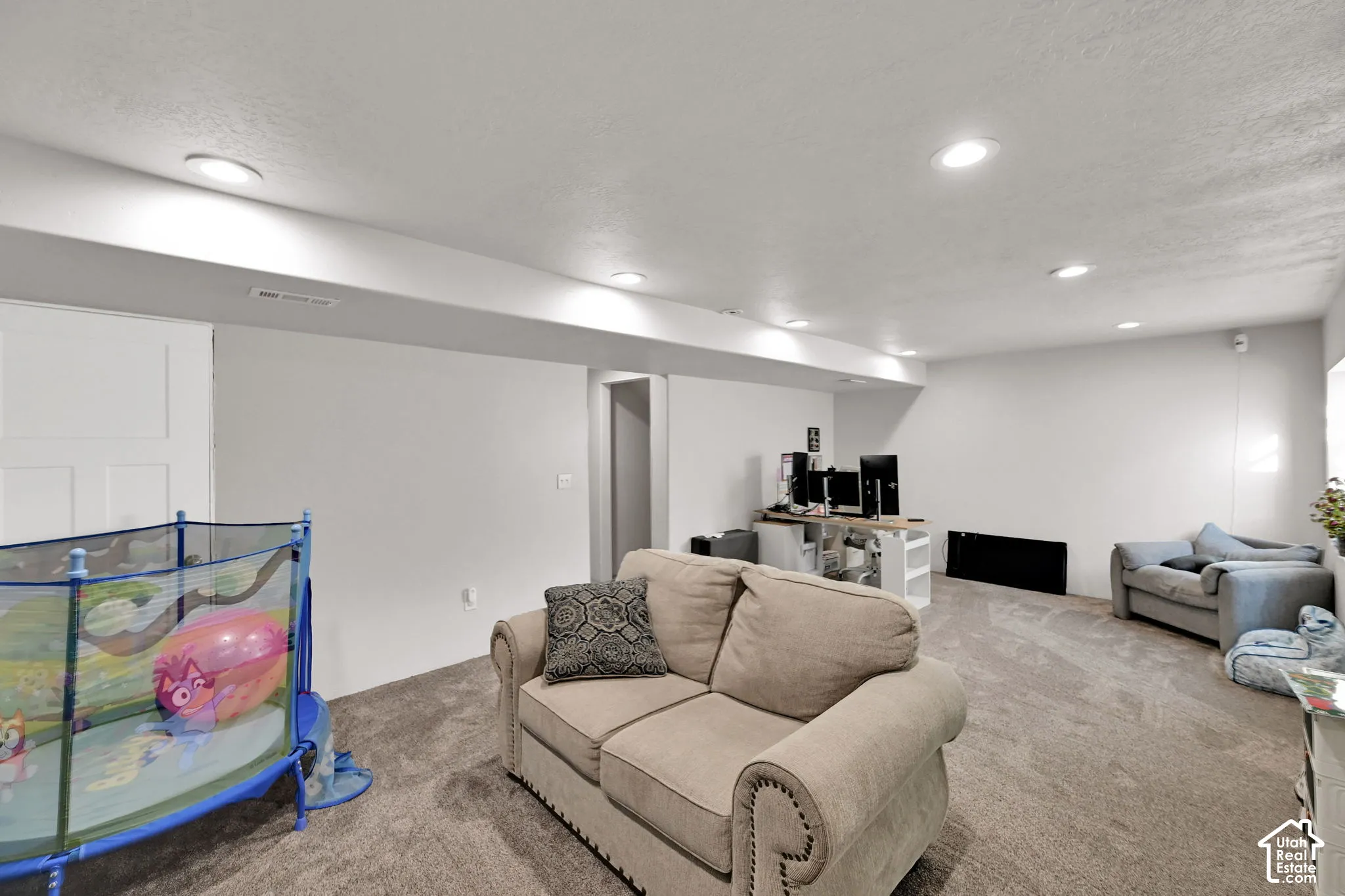 Recessed ceiling lighting illuminates a carpeted room with white walls