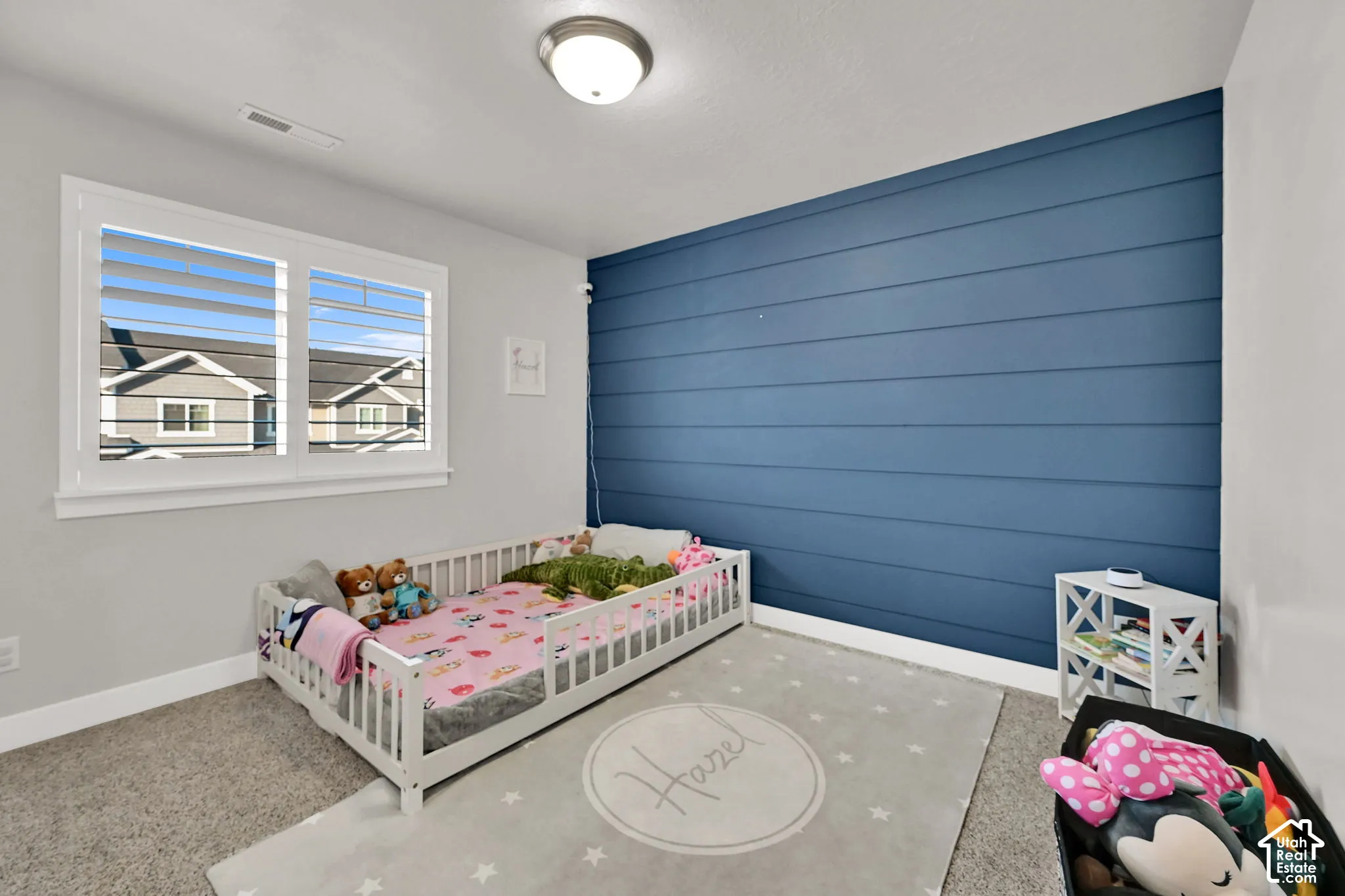 Window with white plantation shutters, accent wall with horizontal paneling, and wall-mounted light fixture