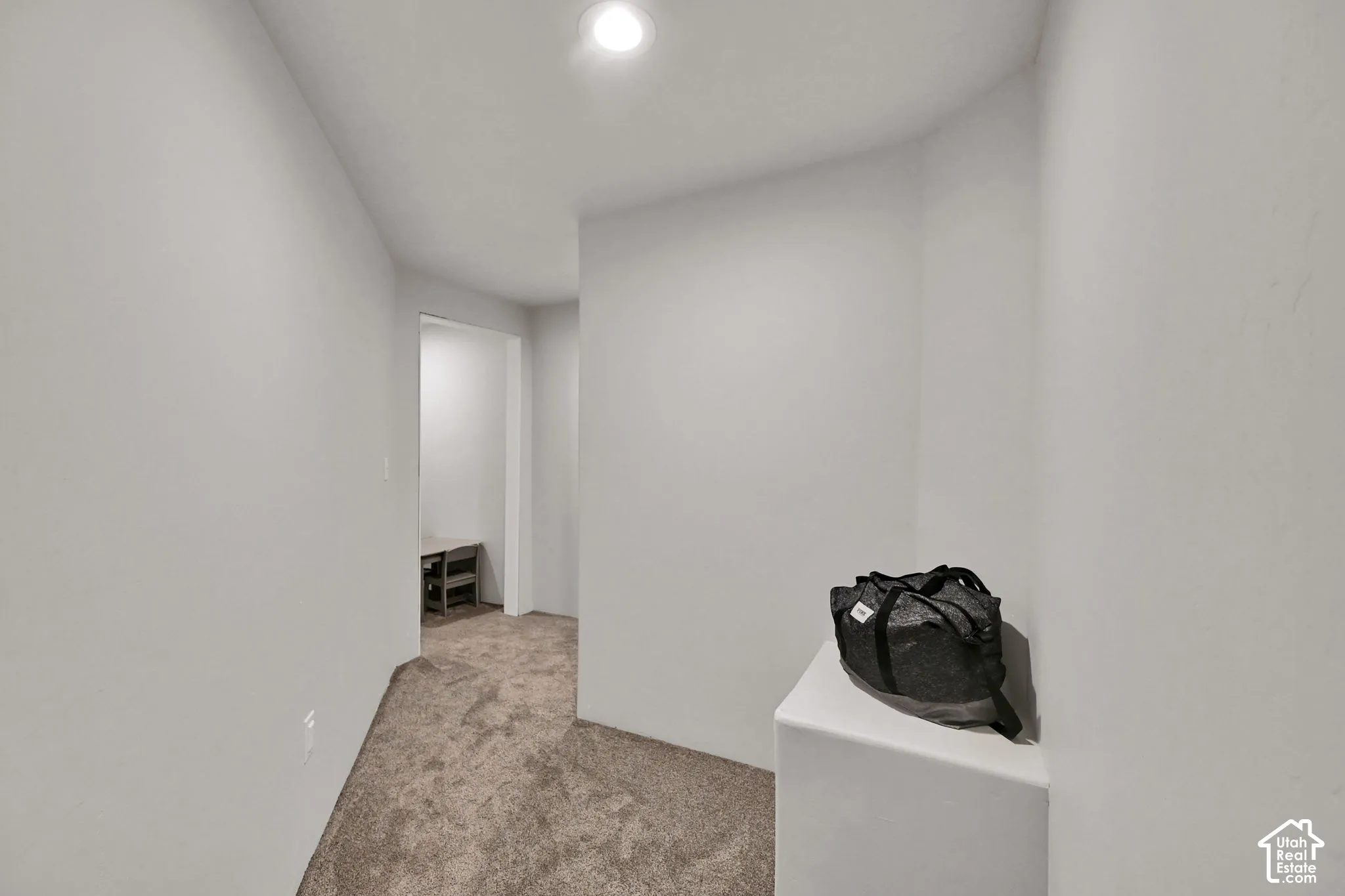 Recessed ceiling lighting illuminating a carpeted hallway with light-toned walls