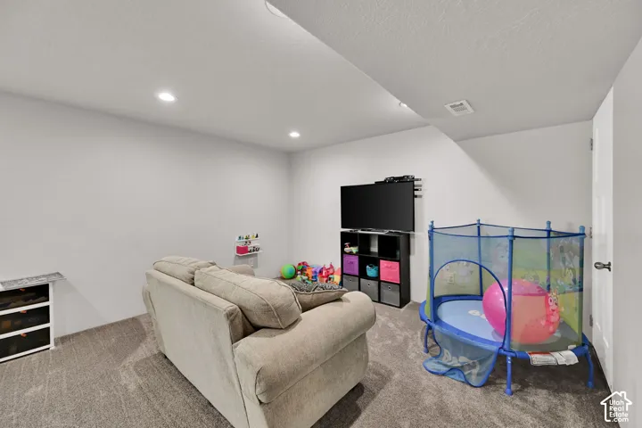 Recessed lighting with a textured ceiling, carpeted flooring, and a built-in media console