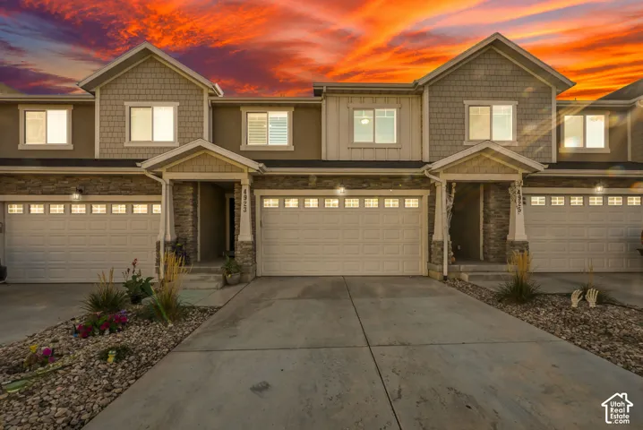 Stone and siding exterior with covered entry, two-car garage, and driveway