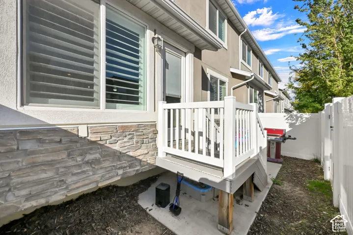 Exterior featuring stone veneer detailing, a white privacy fence, and a private deck with white railings