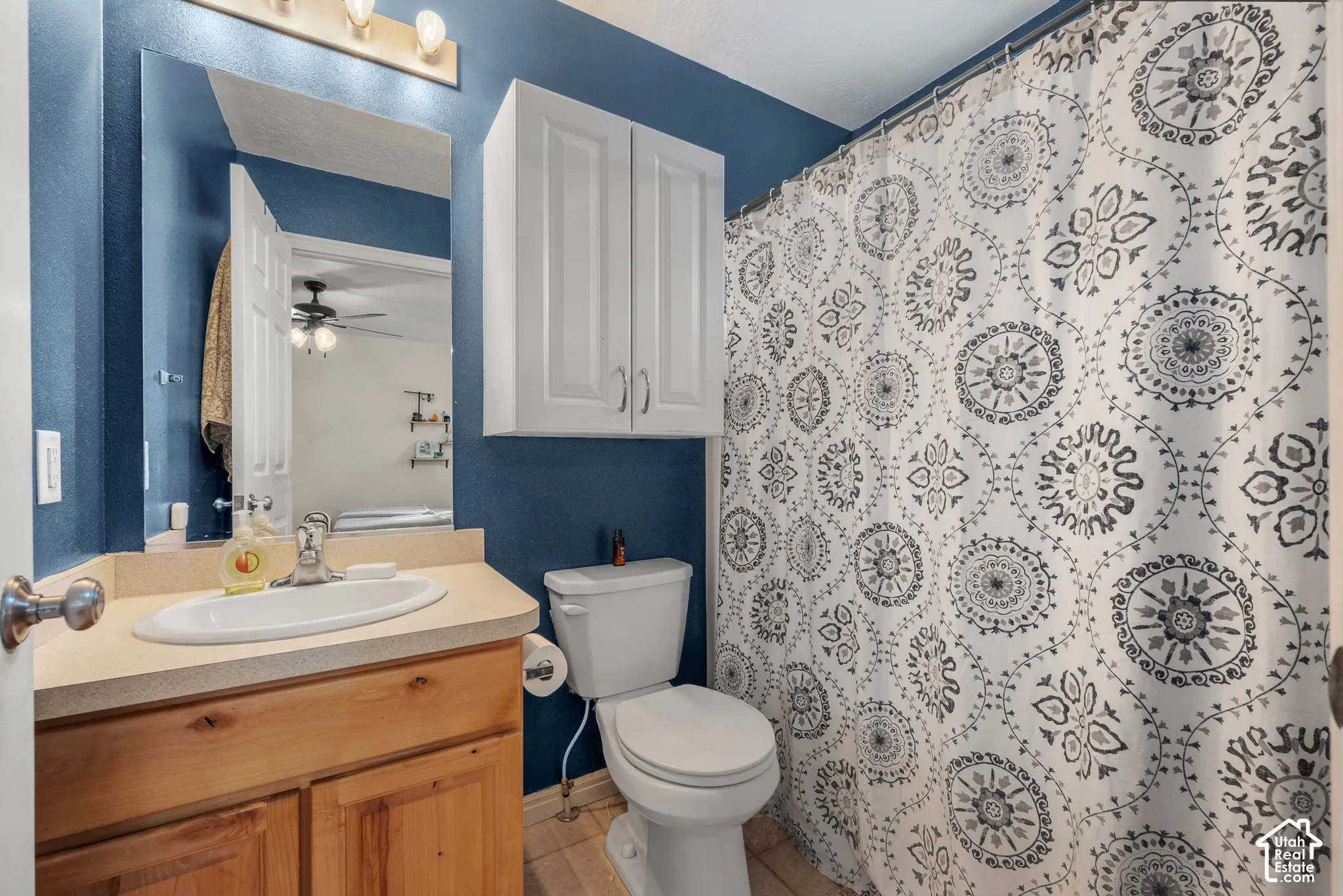 Vanity with a single basin, wood-finish cabinetry, built-in mirror, and overhead lighting