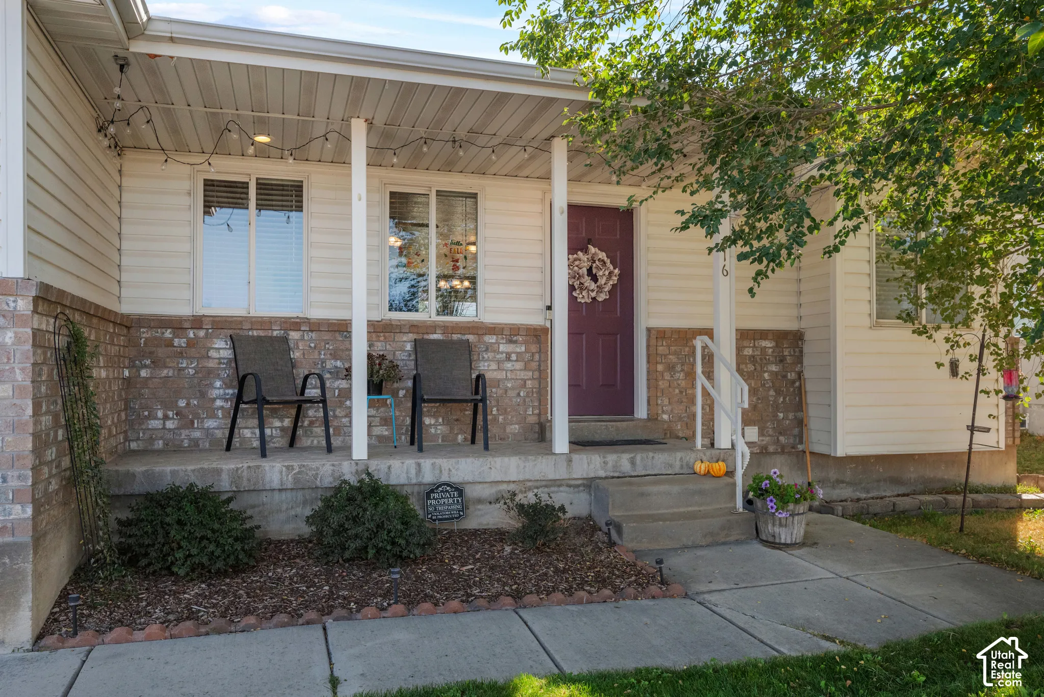 Covered front porch with brick accent siding, white railings, and concrete steps