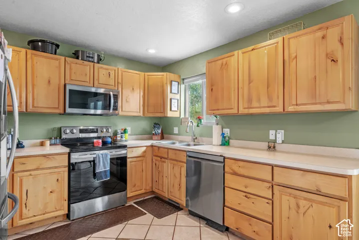 Kitchen featuring wood-finish cabinetry, stainless steel appliances, light-toned countertops, and recessed lighting
