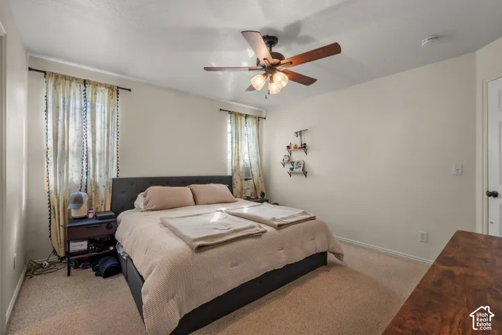 Carpeted flooring, ceiling fan with integrated lighting, and multiple windows