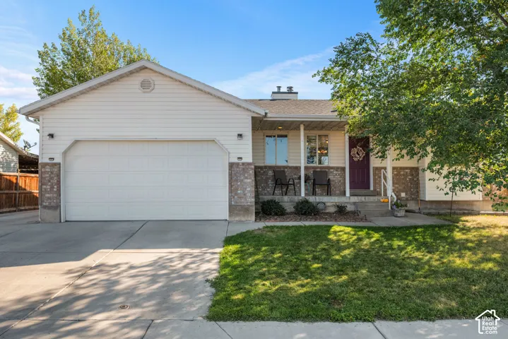 Single-story residence featuring a two-car garage, brick accents, and a covered porch entry
