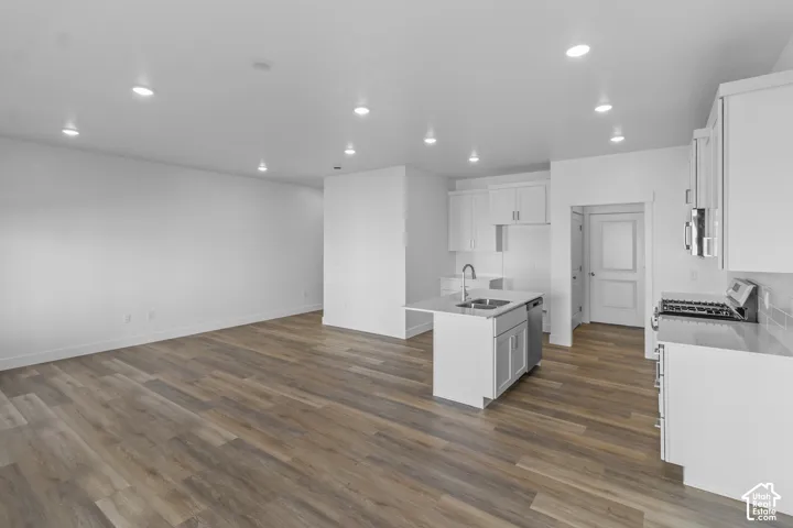 Open-concept living space with wood-finish flooring, recessed lighting, and white walls