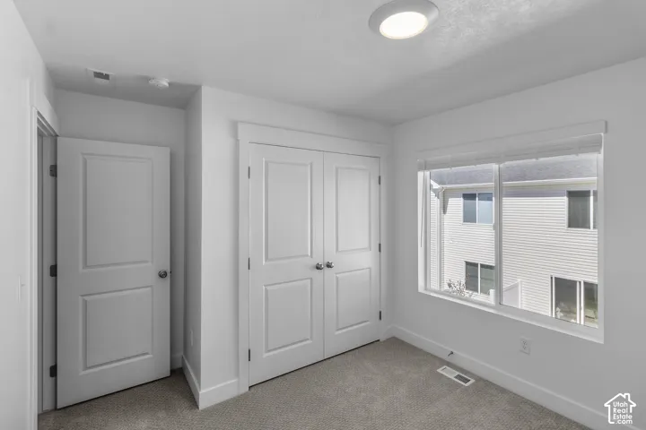 Carpeted flooring, white walls, and a white ceiling light fixture