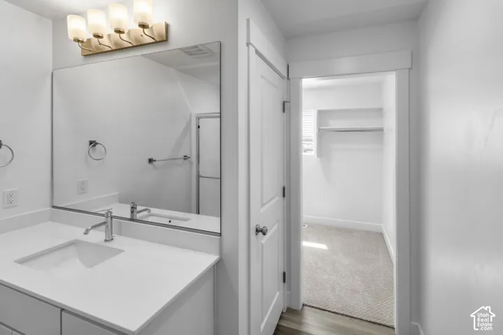 Bathroom vanity with white countertop, undermount sink, and chrome faucet