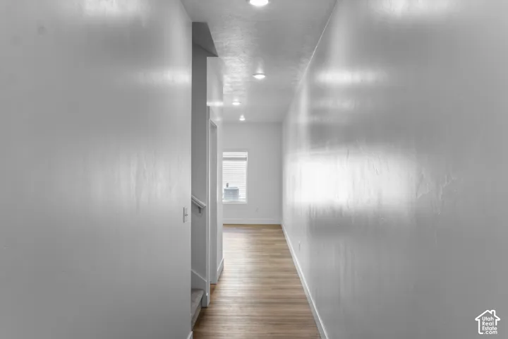 Hallway with recessed lighting, wood-finish flooring, and white walls