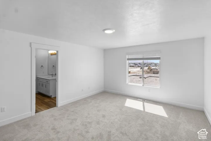 Plush carpeting, recessed lighting, and a single window with blinds