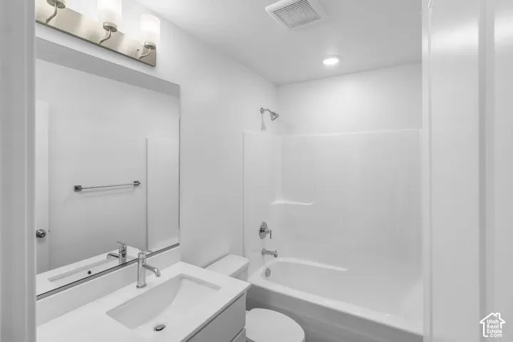 Bathroom featuring a built-in tub and shower combination, chrome fixtures, an integrated vanity sink with a white countertop, a large mirror, and overhead lighting