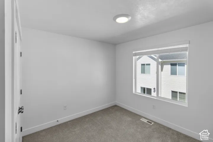 Recessed ceiling lighting, white interior walls, window with blinds, and neutral carpeting