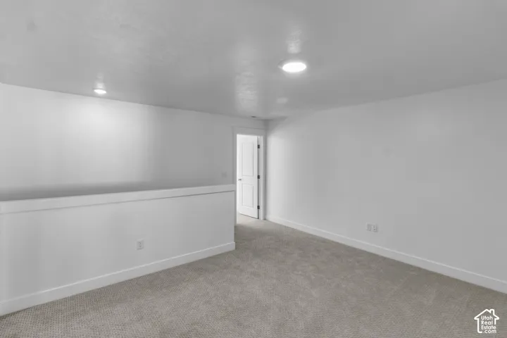Carpeted loft area featuring recessed lighting and a half-wall partition