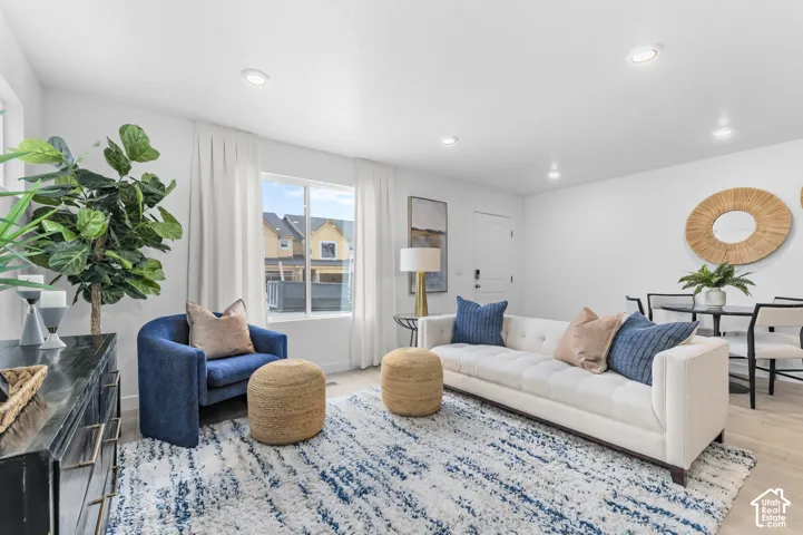 Recessed lighting, light wood-finish flooring, white walls, and a large window with white window treatments