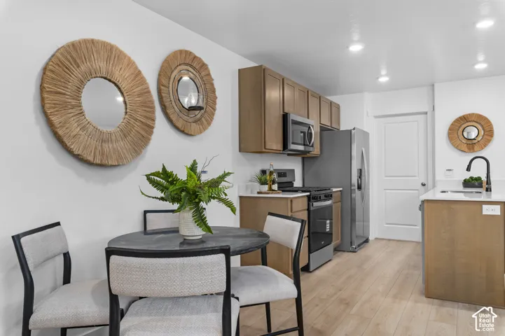 Recessed ceiling lighting illuminates wood-finish flooring, light-toned cabinetry, and stainless steel appliances