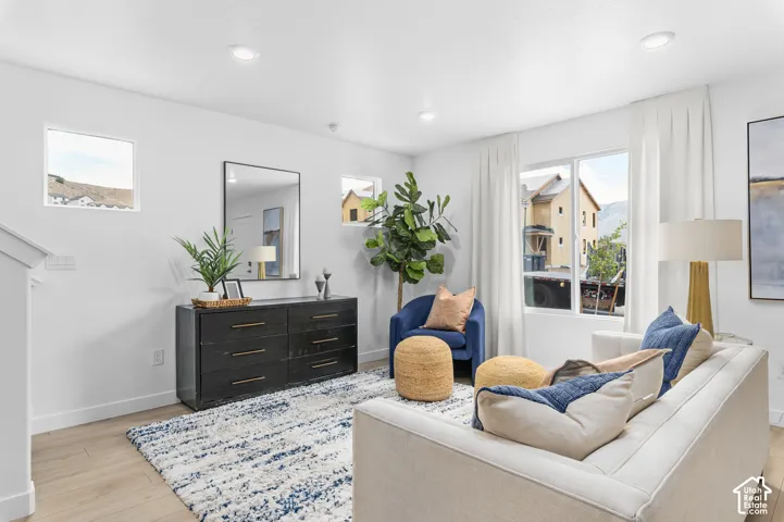 Recessed ceiling lighting, multiple windows, wood-finish flooring, and white walls