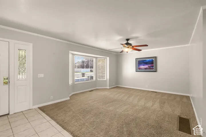 Entry with tiled flooring and decorative glass door panel, bay window, ceiling fan with light fixture, and neutral wall paint